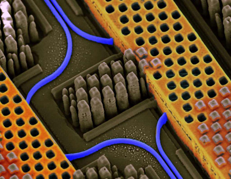 Angled view of a portion of an IBM chip showing blue optical waveguides transmitting high-speed optical signals and yellow copper wires carrying high-speed electrical signals. IBM Silicon Nanophotonics technology is capable of integrating optical and electrical circuits side-by-side on the same chip. 